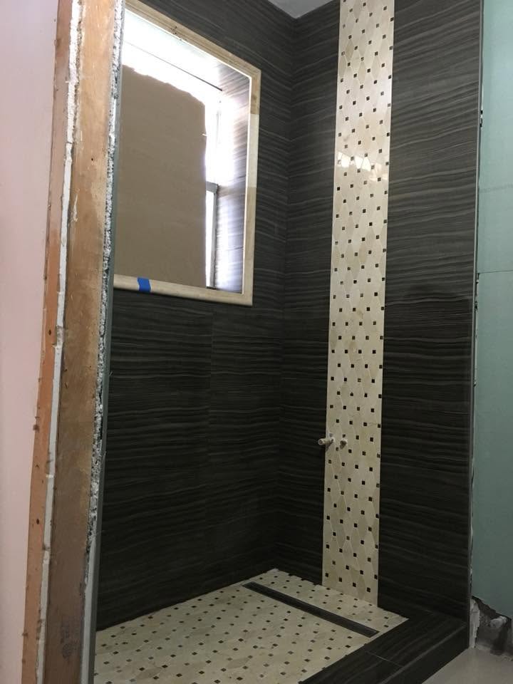 Custom shower by Mederus Services Inc. featuring dark textured tile and a decorative mosaic accent strip