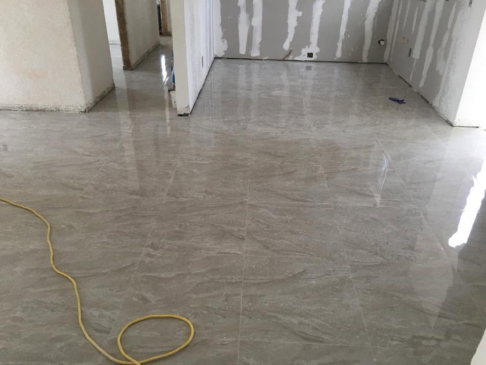 Large-format glossy porcelain tile floor installed by Mederus Services Inc.